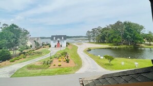A residential area with a house, a curved driveway, a lake, and a grassy area with small trees. - Fairway To Heaven 3 Bedroom Home by RedAwning (Supply)