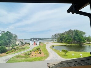 A residential area with a house, a curved driveway, a lake, and a grassy area with small trees. - Fairway To Heaven 3 Bedroom Home by RedAwning (Supply)