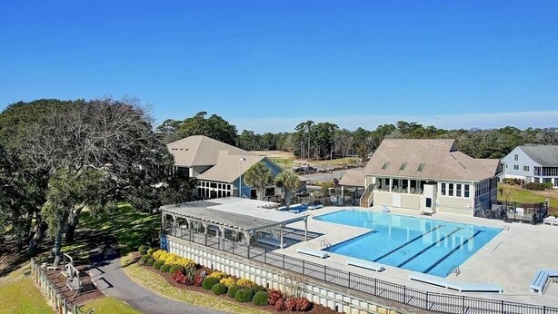 A swimming pool area with a covered deck, adjacent buildings, and a large tree. - Fairway To Heaven 3 Bedroom Home by RedAwning (Supply)