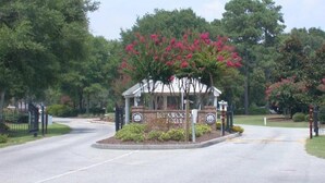 A gated entrance with a sign reading "IC. KWOOK FAMILY" surrounded by lush greenery and flowering trees. - Fairway To Heaven 3 Bedroom Home by RedAwning (Supply)