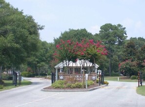 A gated entrance with a sign reading "IC. KWOOK FAMILY" surrounded by lush greenery and flowering trees. - Fairway To Heaven 3 Bedroom Home by RedAwning (Supply)