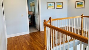 A hallway with wooden flooring, a white railing, and two framed pictures on the wall. - Fairway To Heaven 3 Bedroom Home by RedAwning (Supply)