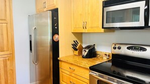 A kitchen with wooden cabinets, a stainless steel refrigerator, a microwave, a toaster, and an oven. - Fairway To Heaven 3 Bedroom Home by RedAwning (Supply)