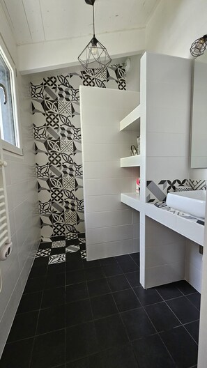 A modern bathroom with black and white patterned tiles, a white vanity, and a hanging light fixture. - Villa with a pool, 7 km from La Rochelle and 15 km from Île de Ré (Dompierre-sur-Mer)