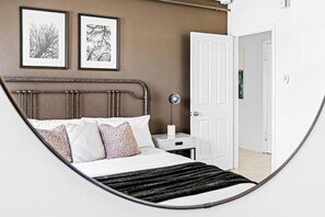 Ein Schlafzimmer mit einem Bett, einem Nachttisch und einer Tür zu einem anderen Raum.