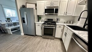 A modern kitchen with white cabinets, stainless steel appliances, and a marble countertop. - Sidelines @ Grand Park Game Room, Outdoor Basketball Court Sleeps 13+ (Sheridan)