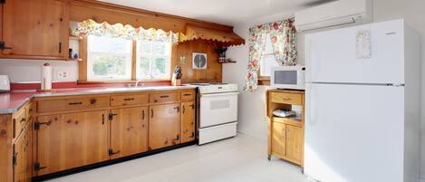 A kitchen with wooden cabinets, a white refrigerator, and a microwave.