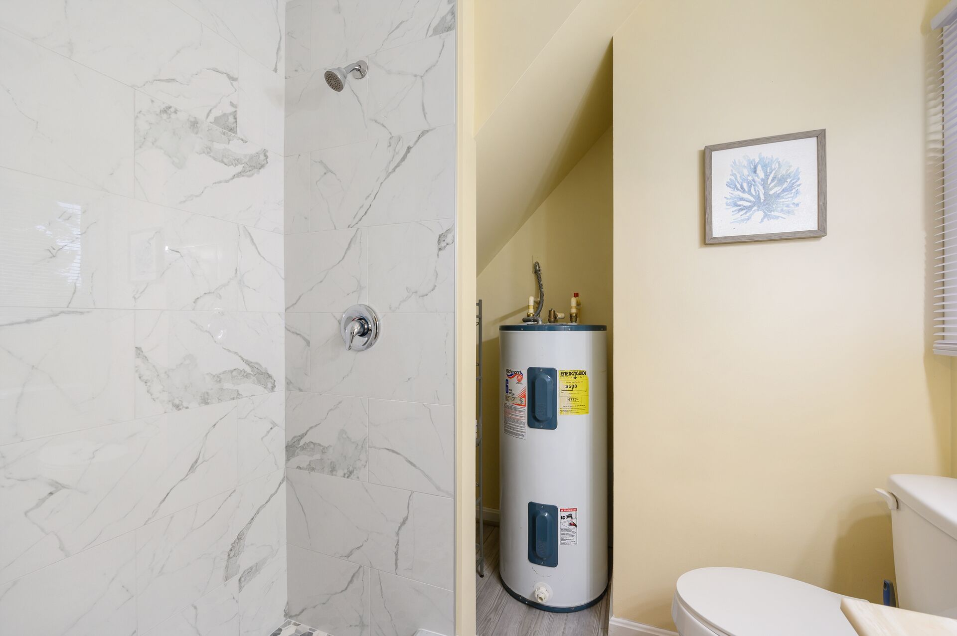 Une salle de bain équipée d’une douche, de toilettes et d’un chauffe-eau.