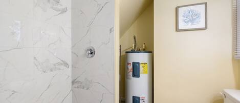 Une salle de bain équipée d’une douche, de toilettes et d’un chauffe-eau.