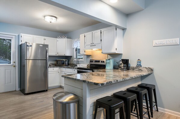 A modern kitchen with white cabinets, stainless steel appliances, and a granite countertop.