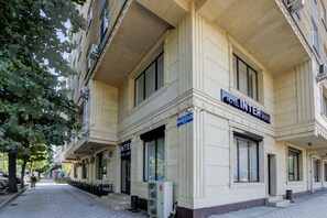 Un bâtiment d’hôtel avec une enseigne indiquant « HÔTEL, AUBERGE, CHAMBRES » et un panneau bleu indiquant une chambre ou une zone spécifique.