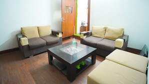 A living room with two sofas, a coffee table, and a door with a green vertical accent. - Roomshala 045 Galaxy Noida 35 (Noida)