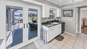 Una cocina moderna con una isla central, muebles blancos y vistas al exterior.