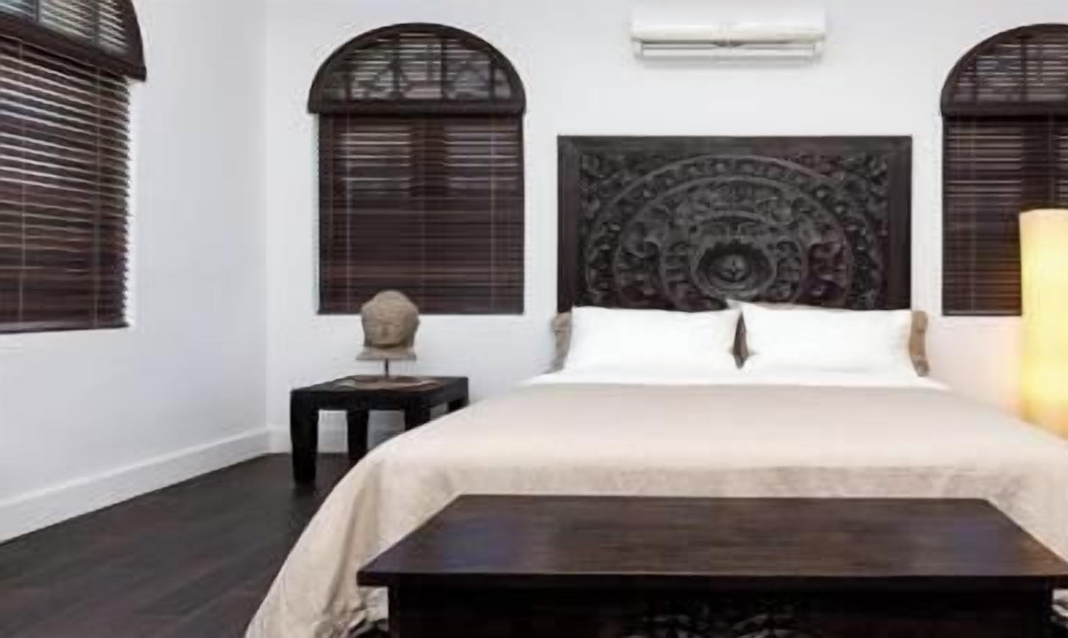 A bedroom with a bed, a nightstand, and a decorative headboard.