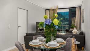 A modern dining area with a glass table set for six, surrounded by grey upholstered chairs. - Stylish and Modern Apartment with City Views (Cape Town)