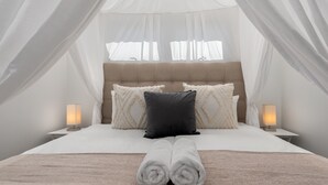 A bed with a canopy, two bedside lamps, and a rolled towel on the bed. - Stylish and Modern Apartment with City Views (Cape Town)