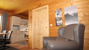 A cozy cabin interior with a dining area, kitchen, and a leather chair.