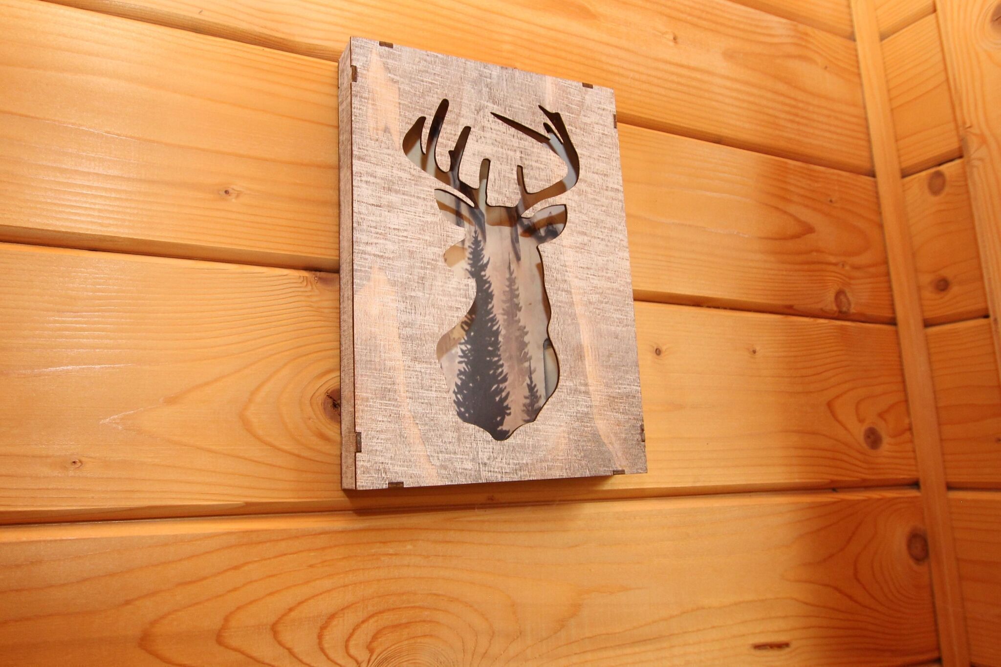 A wooden wall panel with a deer head cutout.