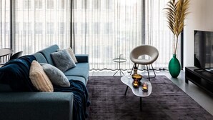 Een moderne woonkamer met een bank, een klein rond tafeltje en een hoge groene vaas.