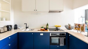 Een moderne keuken met witte bovenkastjes, een blauwe onderkast, een inbouwoven en een spoelbak.