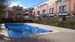A swimming pool with a metal ladder, surrounded by a hedge and a brick building with balconies. - semi-detached house with pool 3 bedrooms near the beach (Platja d'Aro)