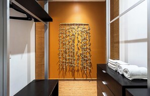Experience a unique bathroom with a decorative wall panel and a wooden bench, offering a clean and contemporary space.