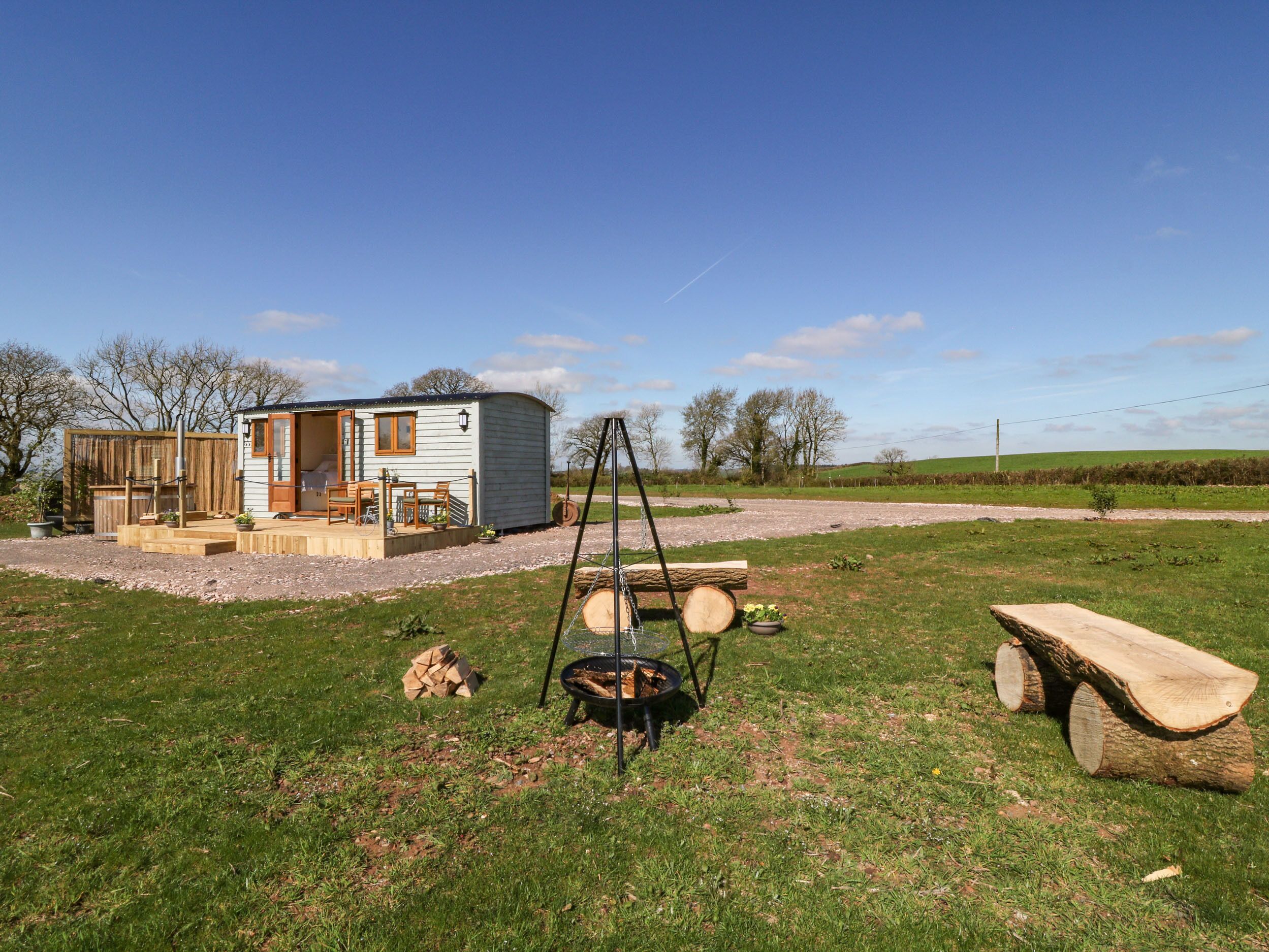 A mobile home with a deck and outdoor seating area, surrounded by a grassy field and trees.