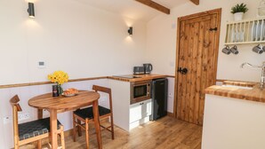 Une cuisine compacte avec un plancher en bois, une table à manger avec des chaises, une machine à café, un four à micro-ondes et un réfrigérateur.