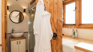 Une salle de bain avec des murs en bois, un lavabo blanc, un miroir et une douche.