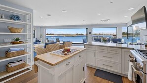 Een moderne keuken met een groot schiereiland, witte kasten en uitzicht op het water.
