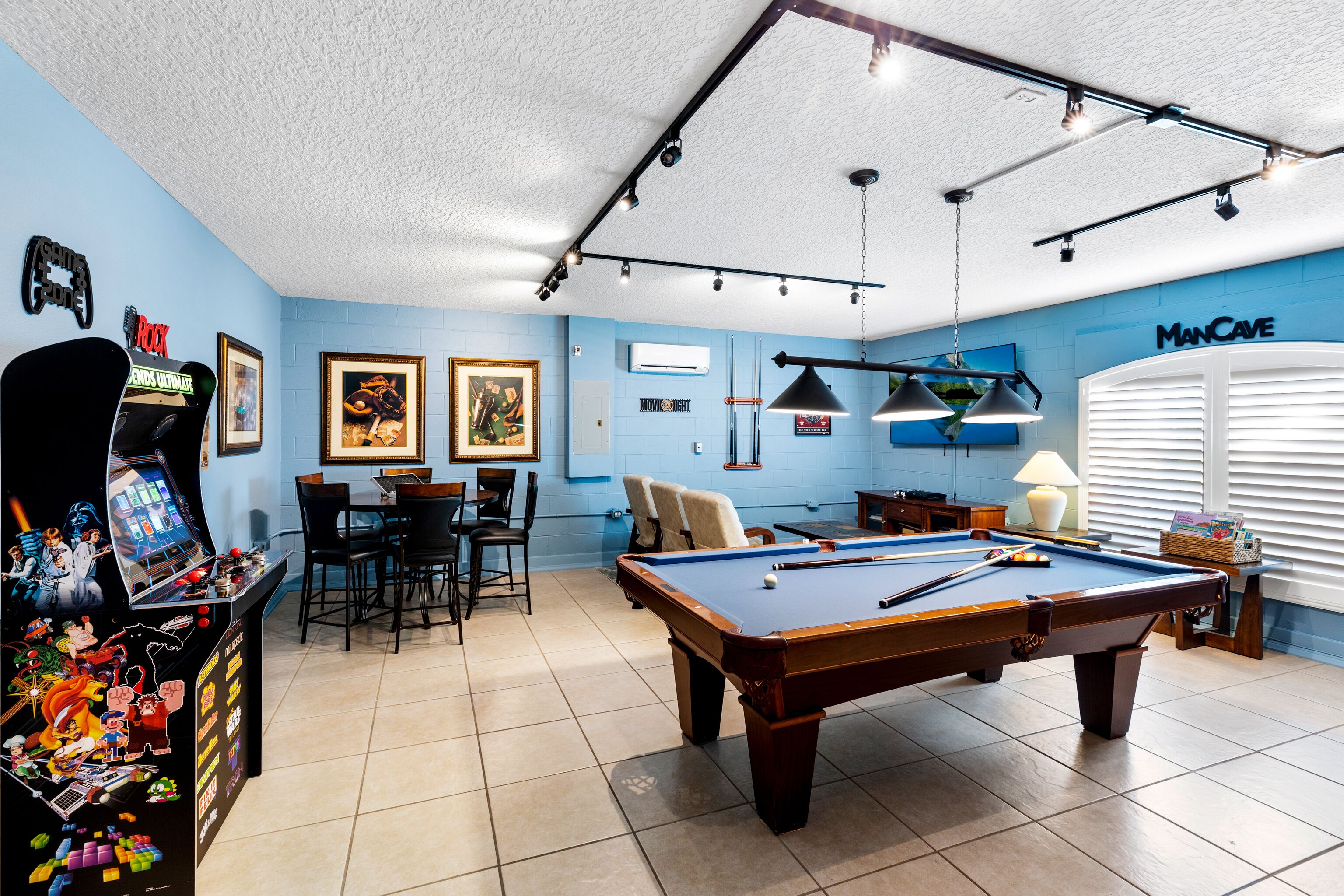 A pool table in a room with blue walls, a ceiling-mounted light fixture, and a 'Man Cave' sign.