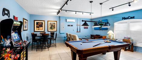 A pool table in a room with blue walls, a ceiling-mounted light fixture, and a 'Man Cave' sign.
