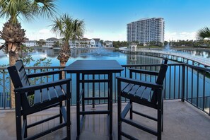 Enjoy a serene view of the calm body of water surrounded by a beautifully maintained garden with palm trees.