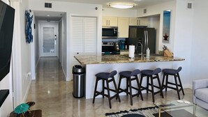 A modern kitchen with a central island, bar stools, a microwave, and a refrigerator. - Ocean Views at Ocean Pointe 
Tavernier, FL (Tavernier)