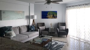 A living room with a sofa, armchairs, a coffee table, a floor lamp, and a ceiling fan. - Ocean Views at Ocean Pointe 
Tavernier, FL (Tavernier)