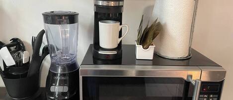 A kitchen with a blender, coffee maker, and microwave.