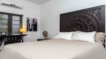 Une chambre à coucher avec un grand lit, une table de chevet, une lampe, un tableau encadré et une tête de lit décorative.