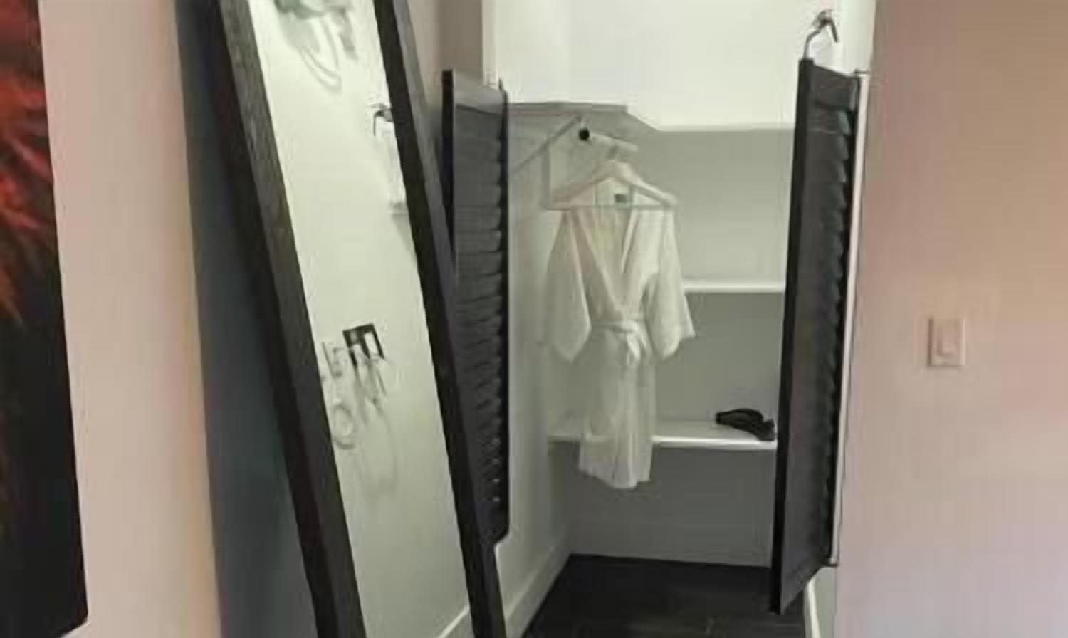 A bathroom with a white robe hanging on a rack, a white sink, and a dark floor.