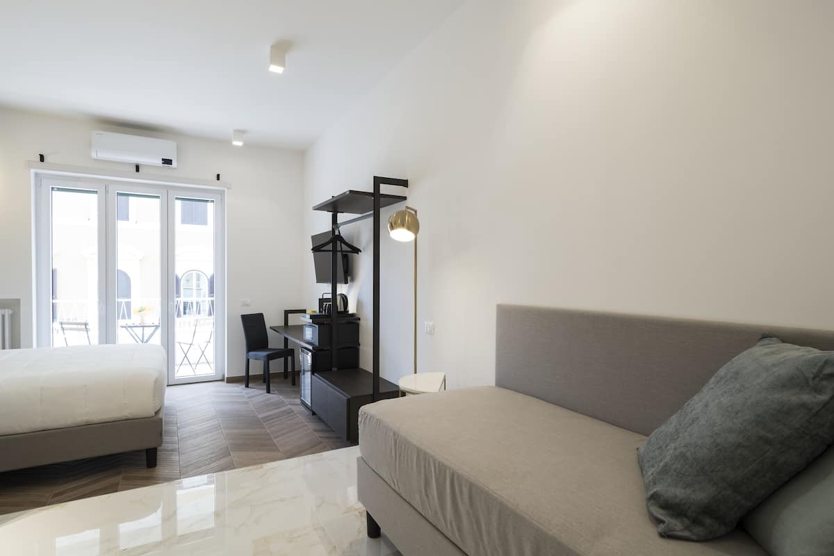 A modern, well-lit room with a sofa, a dining table, and a kitchen area.