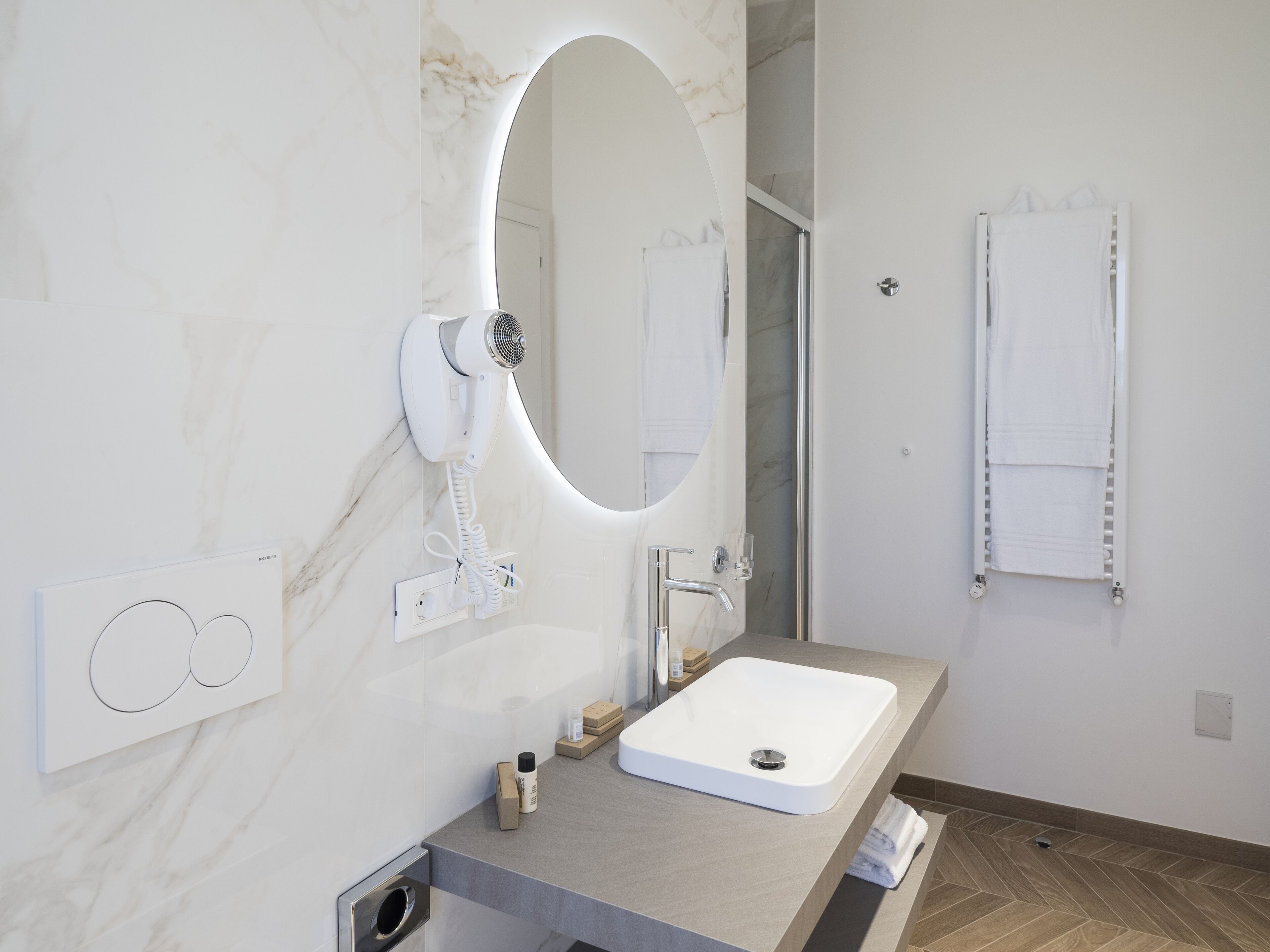 Un bany modern amb una paret de marbre, un lavabo integrat, un assecador de cabells i un suport per a tovalloles.