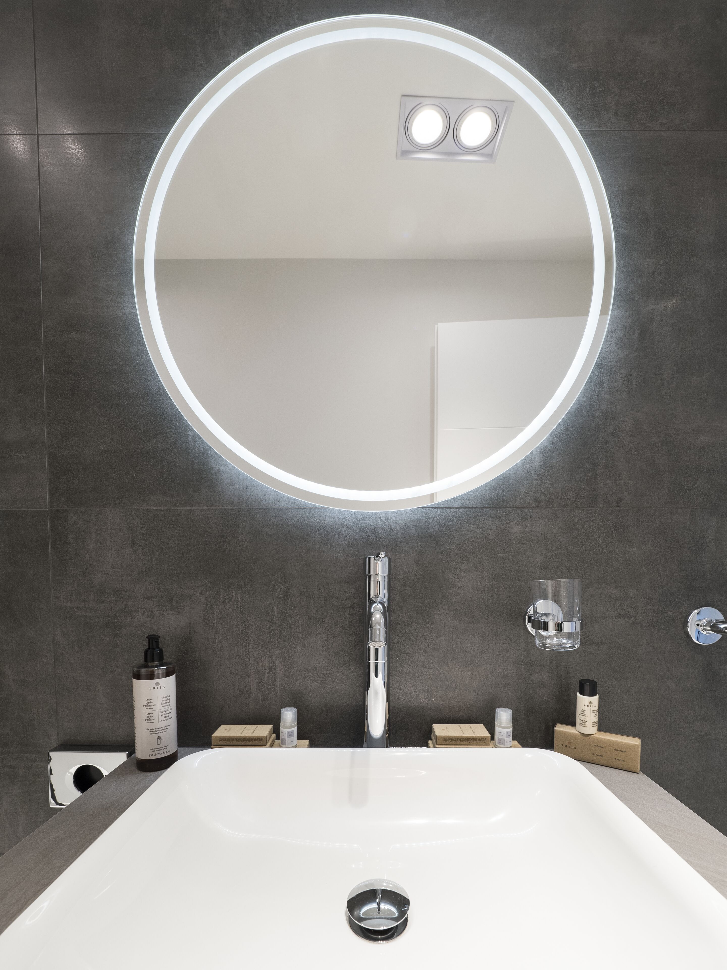 A modern bathroom with a large mirror, a white sink, and a glass shower enclosure.