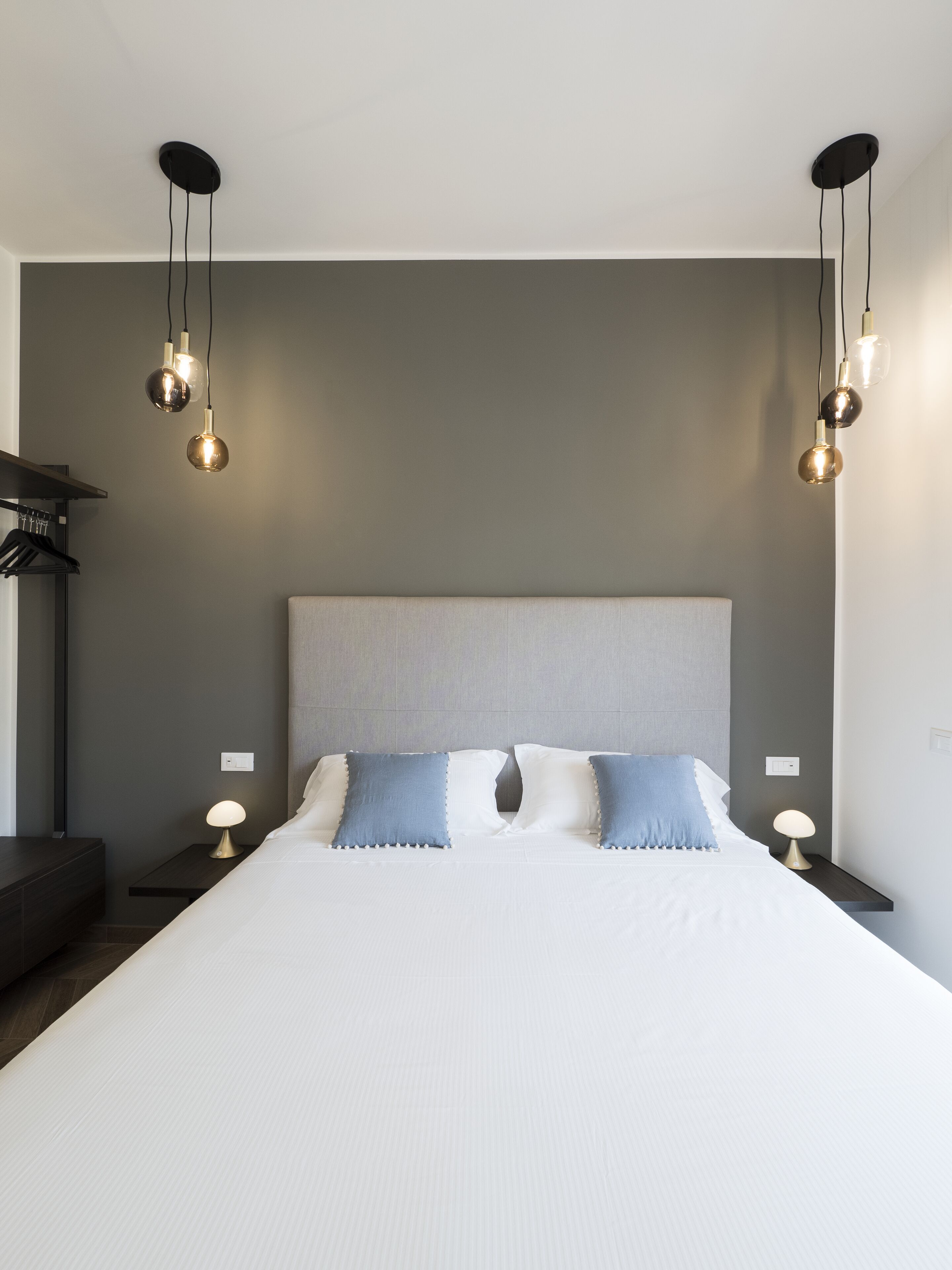 Un dormitorio moderno con una cama grande, dos mesitas de noche y lámparas colgantes.