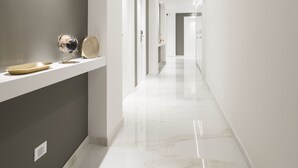 A modern hallway with a marble floor, recessed lighting, and a shelf with decorative items. - Savoia Rooms Roma (Rome)
