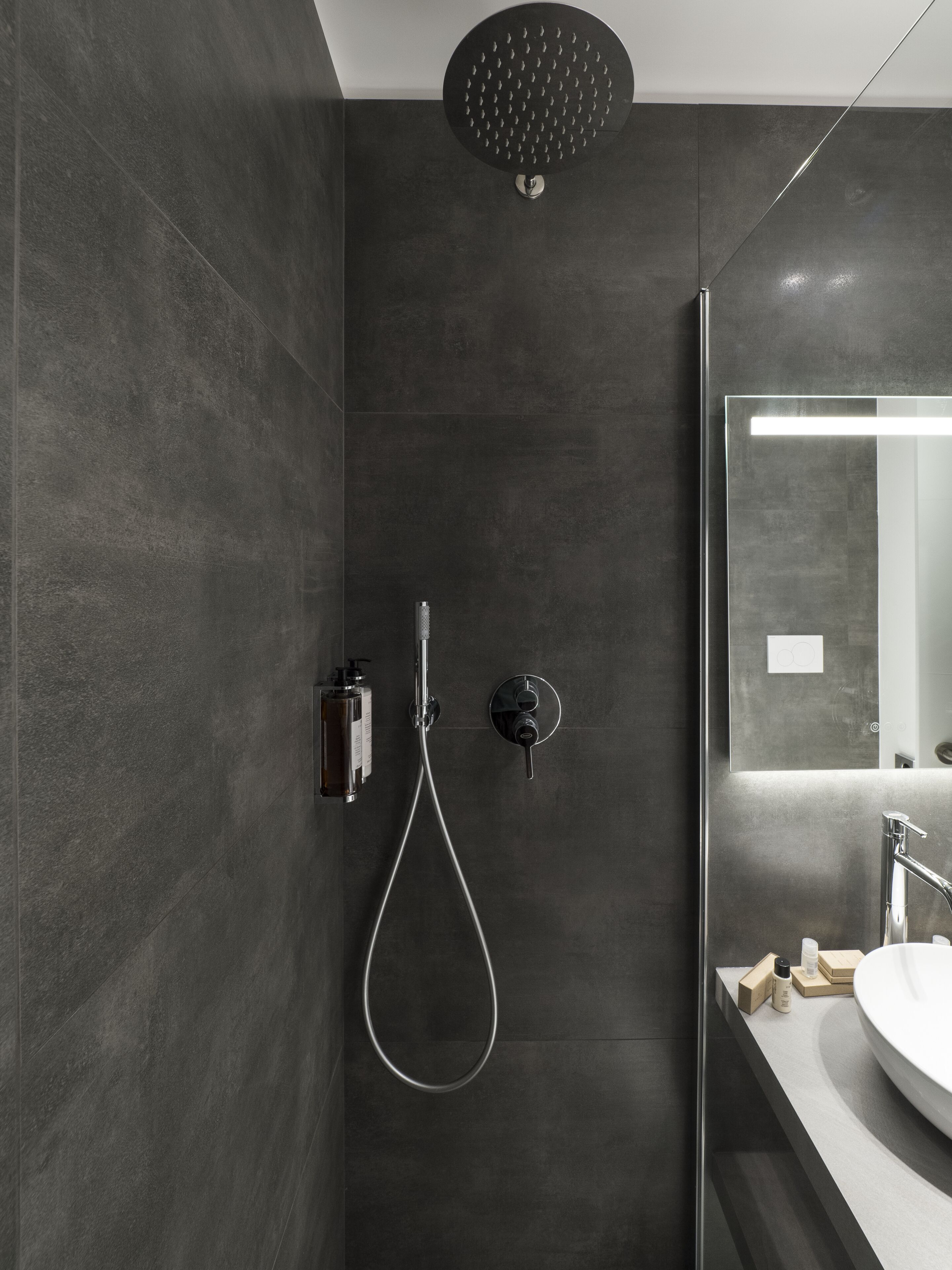 Een moderne badkamer met een douche, wastafel en spiegel.