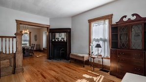 A spacious room with hardwood flooring, a fireplace, a wooden bench, a large wooden cabinet, and a dining area in the background. - Kent Family Home | Walk to Downtown + Pet Friendly (Kent)