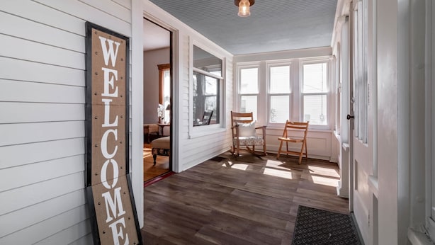 A room with a 'WELCOME' sign, wooden flooring, a dining table with chairs, and large windows. - Kent Family Home | Walk to Downtown + Pet Friendly (Kent)