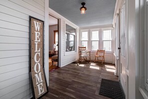 A room with a 'WELCOME' sign, wooden flooring, a dining table with chairs, and large windows. - Kent Family Home | Walk to Downtown + Pet Friendly (Kent)