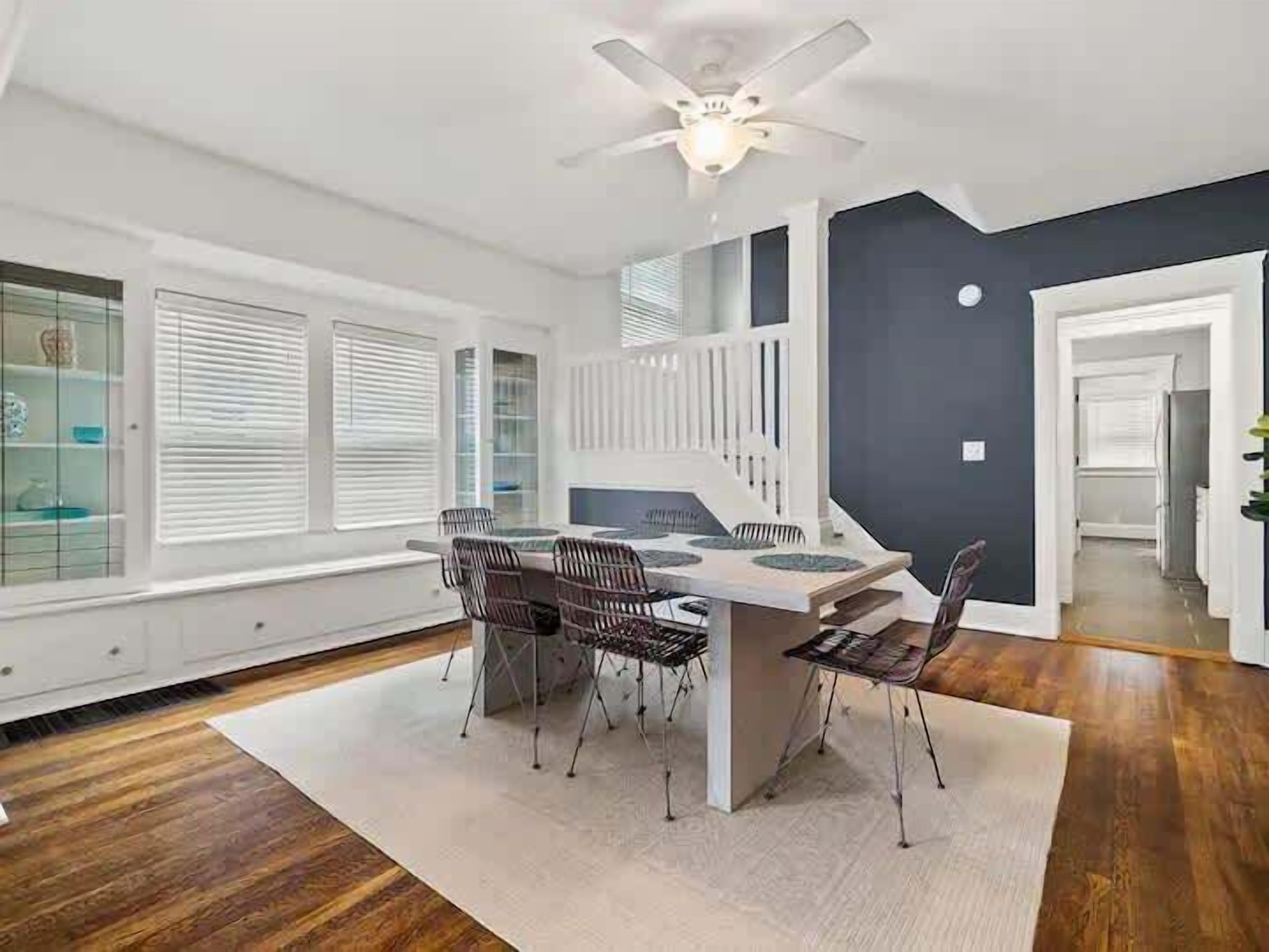 A modern dining area with a white table and chairs, a ceiling fan, and a view of the adjacent room.