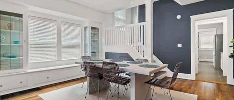 A modern dining area with a white table and chairs, a ceiling fan, and a view of the adjacent room.