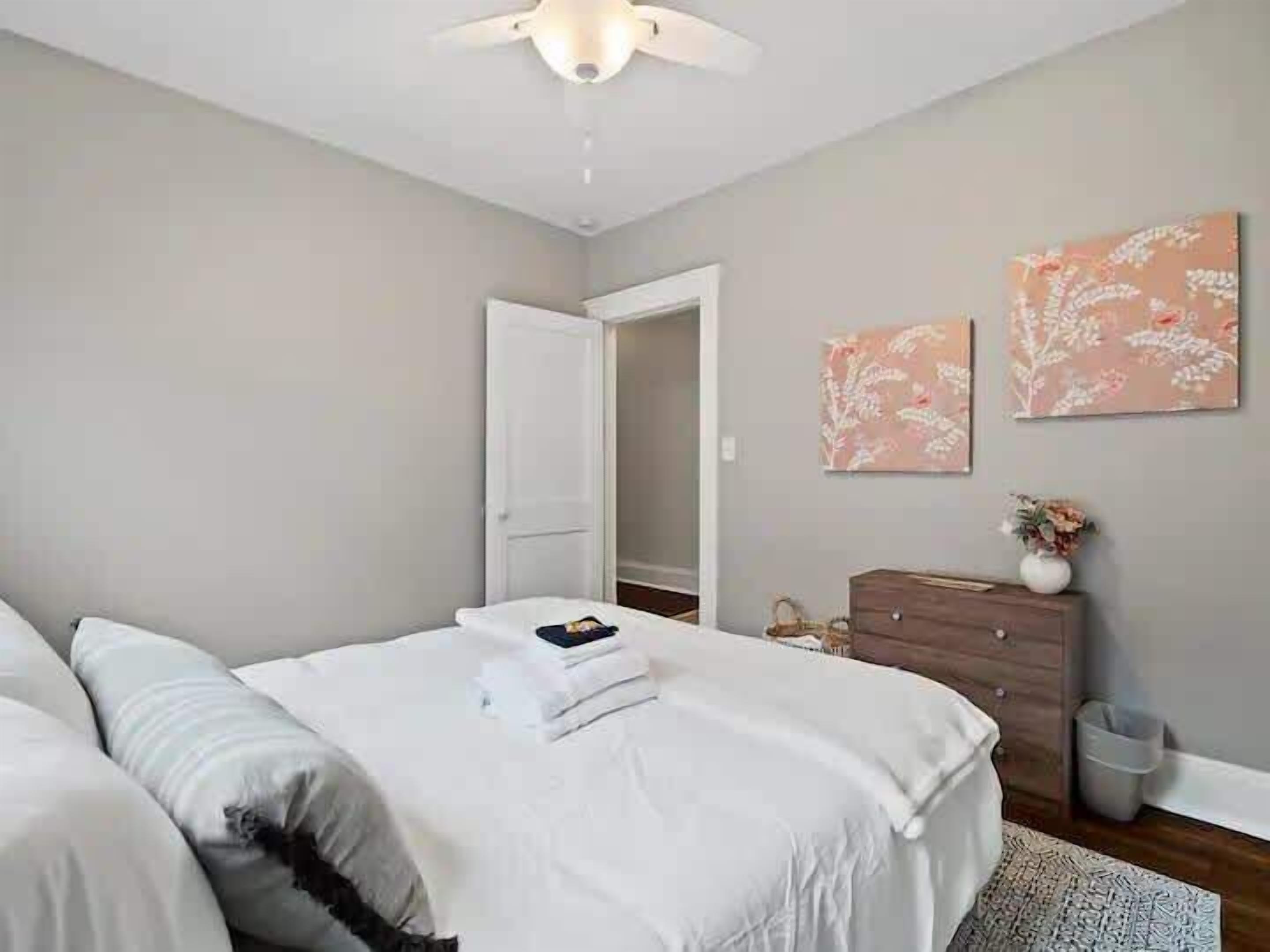 A bedroom with a bed, a dresser, and two wall-mounted floral paintings.